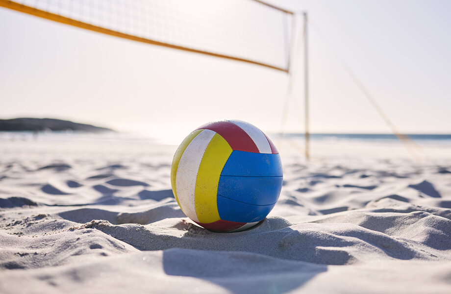 Ein Beachvolley-Ball liegt im Sand unter einem Beachvolleyball-Netz