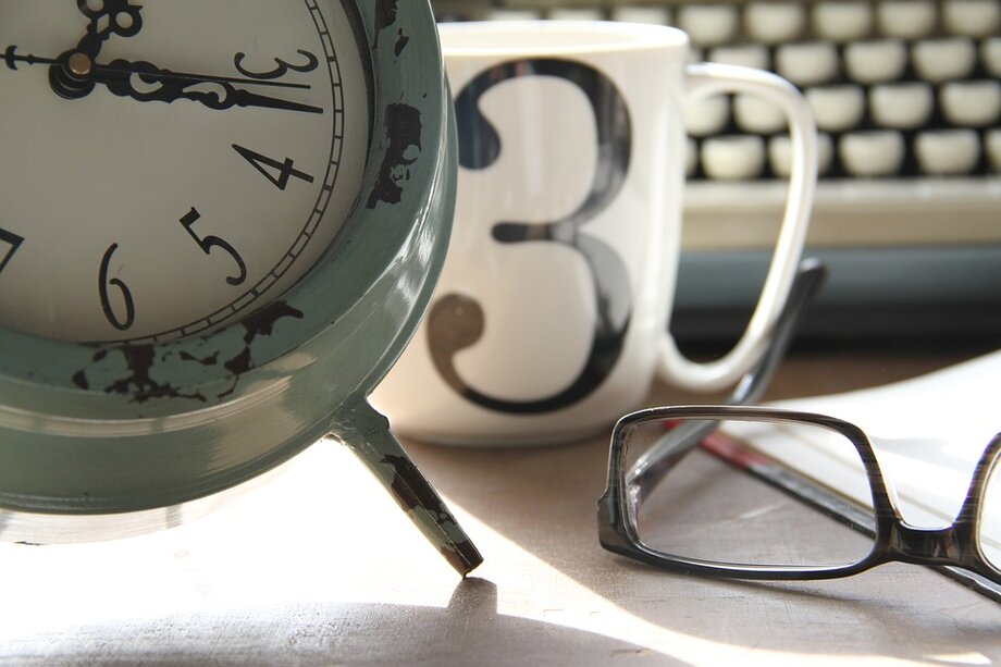 Uhr, Tasse, Brille auf einem Tisch